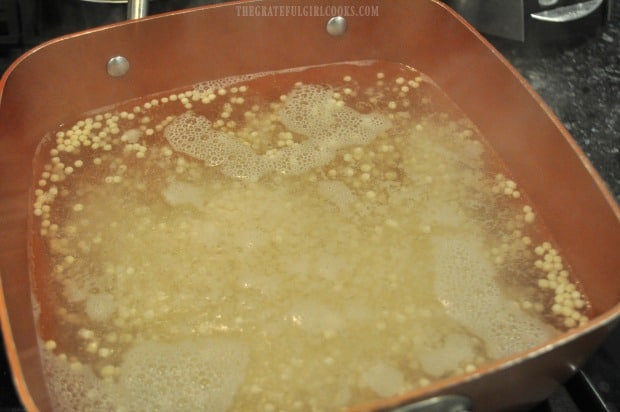 Couscous is cooked in water in pan for lemon herb couscous salad.