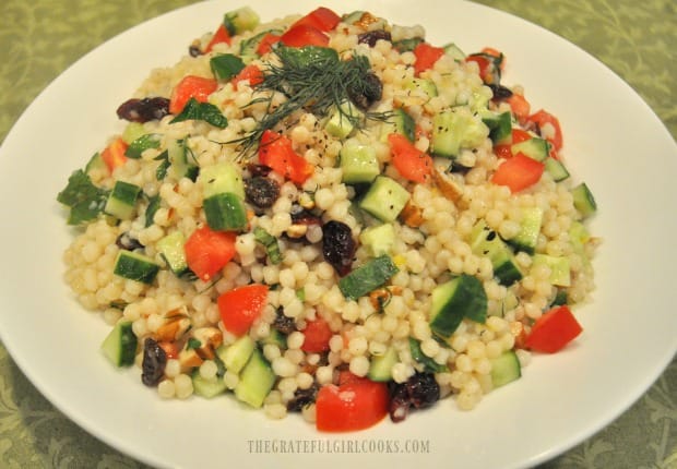 Lemon herb couscous salad in white bowl, with fresh dill garnish on top.