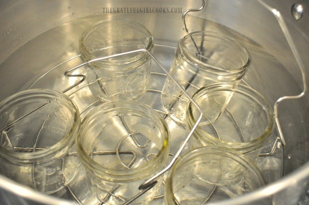 Glass jars are heating in water bath canner before pears are added to hot jars.