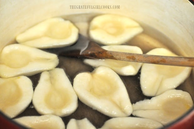 Pear halves are heated in a light syrup before canning.