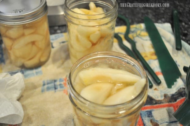 Pear slices are added to jars, along with light syrup.