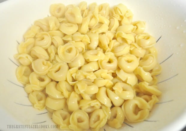 Cheese tortellini is cooked then drained before adding it to skillet.