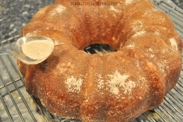 Cinnamon sugar topping is added to top and sides of baked apple cider bundt cake.