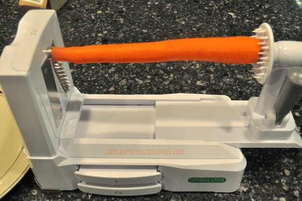 A machine can be used to shred fresh carrots for spiralized carrot salad.