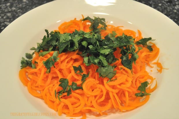 Fresh chopped flat leaf parsley is added to spiralized carrots for salad.