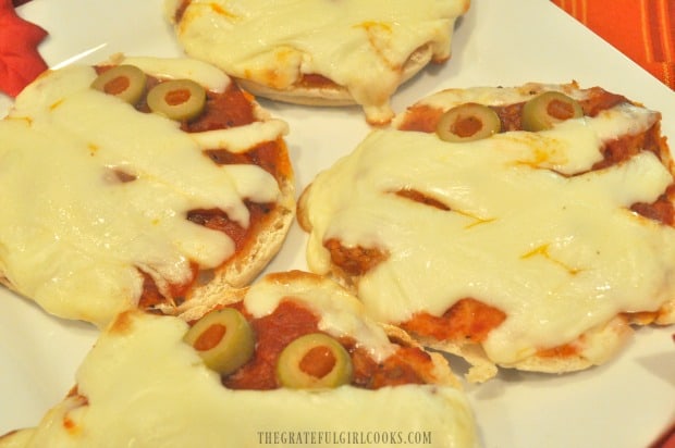 Close up picture of English muffin mummy pizzas on white plate, once baked.