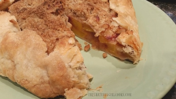 One piece has been cut out of the peach galette, revealing the peaches inside.