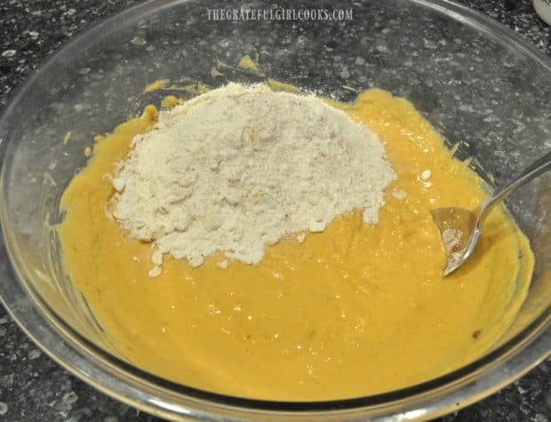 Dry ingredients are added to batter for pumpkin chocolate chip muffins.