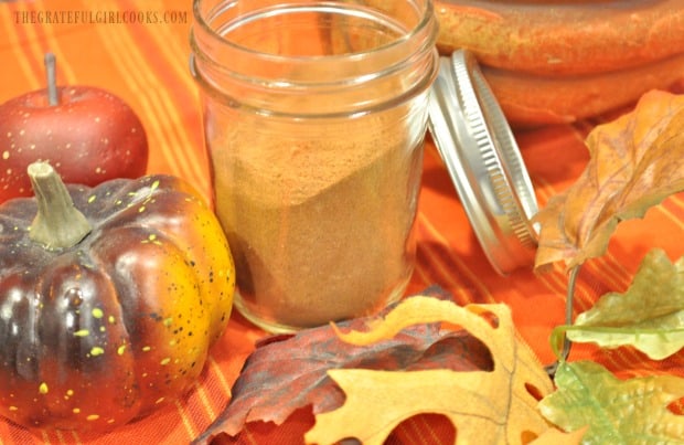 Pumpkin pie spice mix in jar, by Fall apples and leaves.