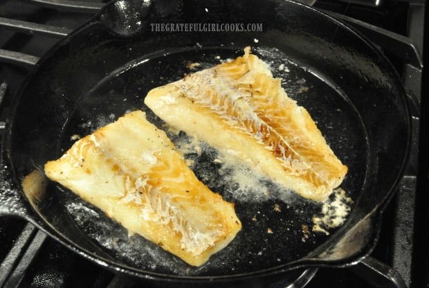 Roast cod is turned over in skillet halfway through the cooking process.