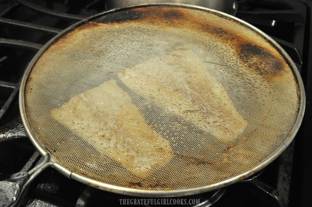 A splatter screen helps the oil not to splash out while cooking roast cod.