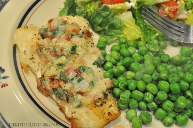 Roast cod with garlic bacon butter is served with a salad and green peas.