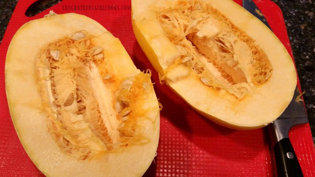 Spaghetti squash is cut in half lengthwise to remove seeds.