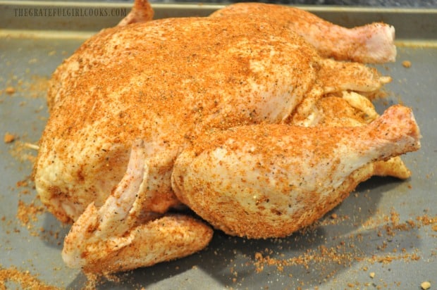 Whole chicken with spice rub mixture, ready to be roasted on Traeger grill.