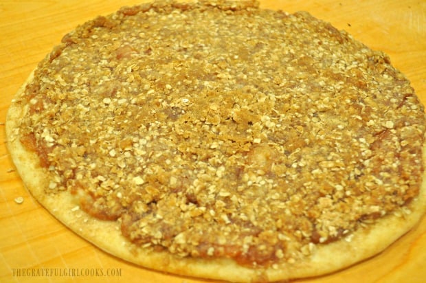 Apple pie dessert pizza is baked and ready to drizzle with icing.