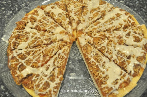 Apple pie dessert pizza with one slice removed, on serving platter.