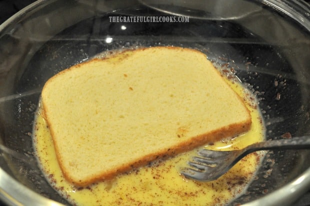 Bread is placed into egg batter to coat it for making classic french toast.