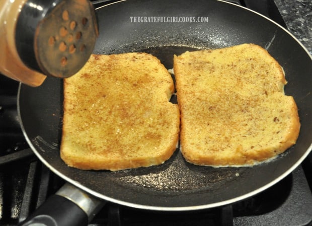 Classic french toast is placed into hot skillet to cook, and sprinkled with cinnamon.