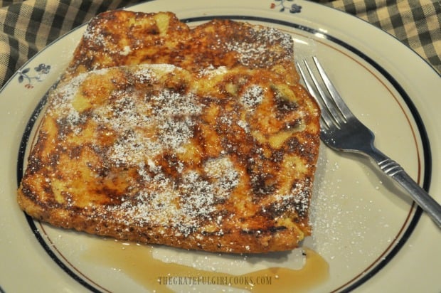 Classic french toast is served hot, with powdered sugar garnish and maple syrup.