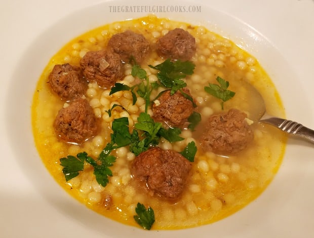 Moroccan meatball couscous soup, served with parsley garnish.