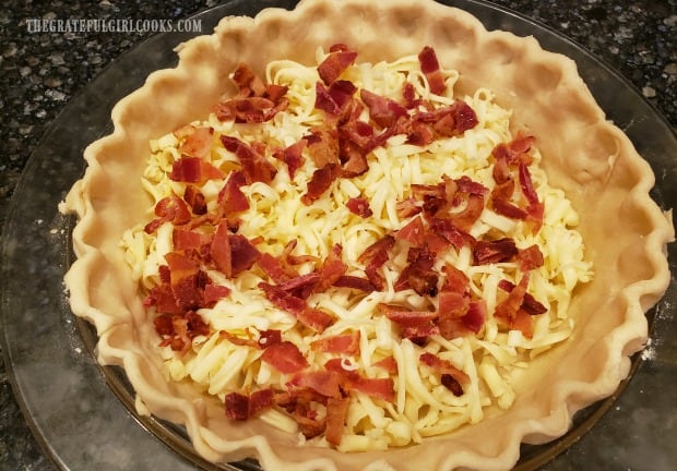 Cooked bacon crumbles and jack cheese, in pie crust, for Southwestern bacon quiche.