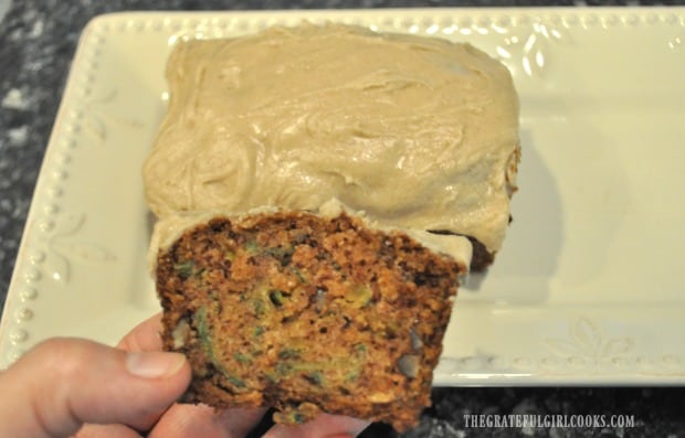A slice of one of the mini zucchini loaves is held in hand before eating!