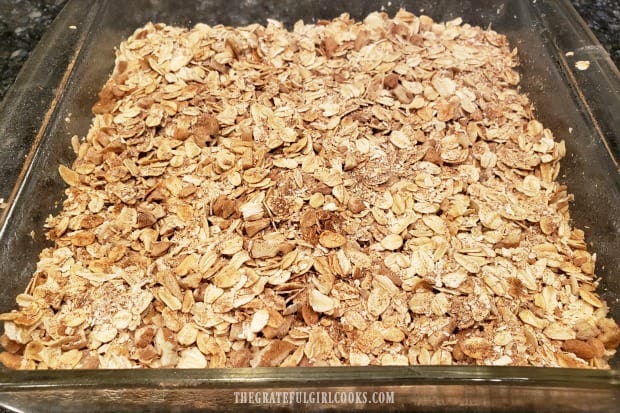 Dry mixture of oats, spices and pecans placed on top of blueberries and apples in dish.