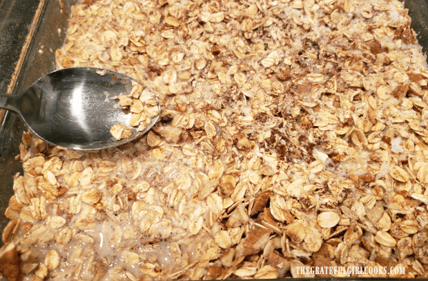 Milk mixture is added to blueberry baked oatmeal dish, and oats are pressed down into liquid.