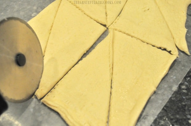 Slicing crescent roll dough into triangles to make the crescent roll coffeecake.