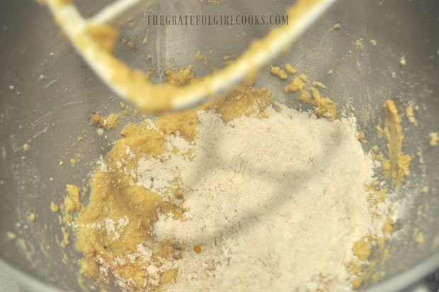 Flour and spices are added to oatmeal cranberry pecan cookies dough.