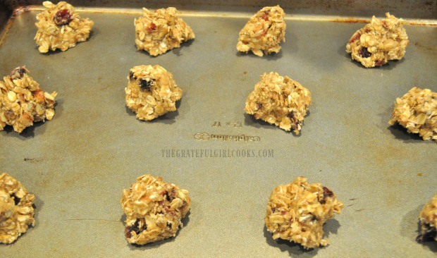 Oatmeal cranberry pecan cookie dough is placed in spoonfuls on baking sheet.