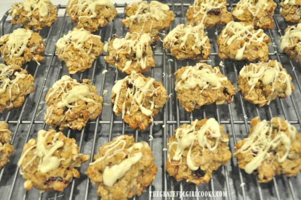 Oatmeal cranberry pecan cookies, drizzled with white chocolate, on wire rack after baking.