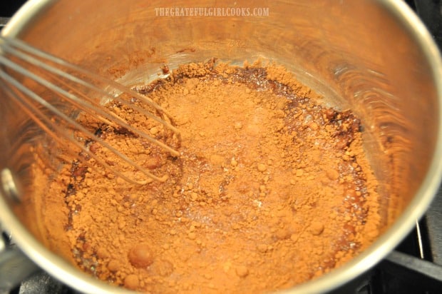 Whisking cocoa powder, milk and sugar in saucepan for Valencia orange hot chocolate.
