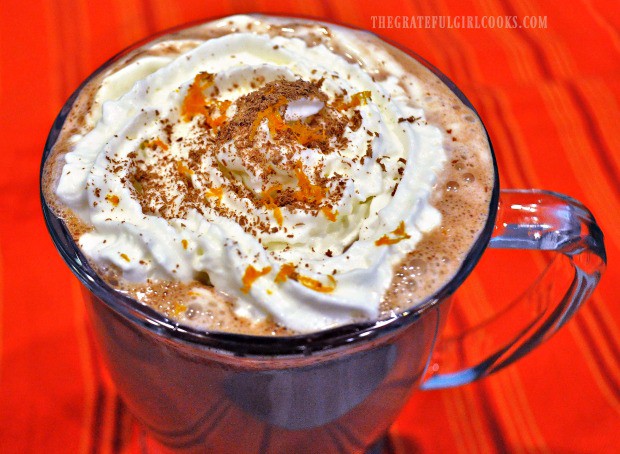 Whipped cream, orange zest, and zested chocolate top a mug of Valencia orange hot chocolate.