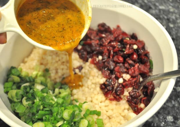 Orange herb vinaigrette is added to the Israeli couscous salad, to mix in.