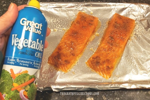 Seasoned salmon fillets are spritzed with non-stick baking spray before being broiled.