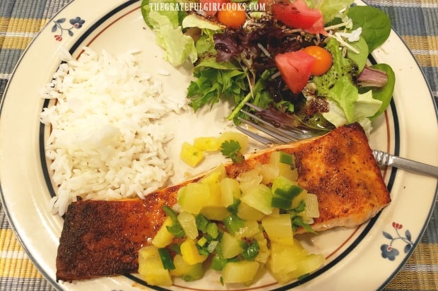 Broiled salmon with pineapple salsa, served on plate with rice and green salad.