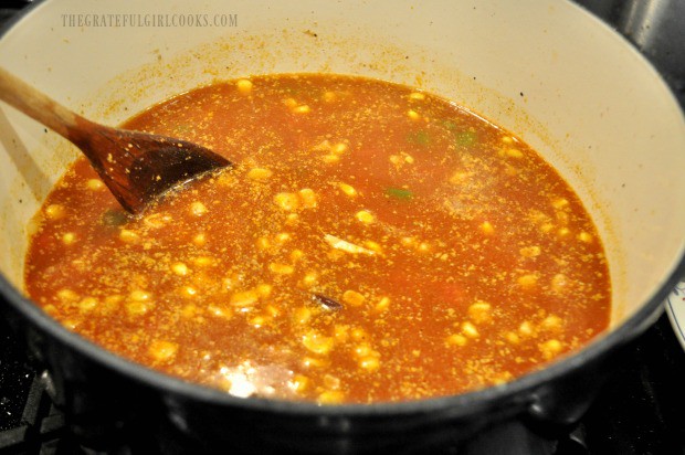 Broth, tomatoes and corn are added to the pan of Southwestern chicken soup.