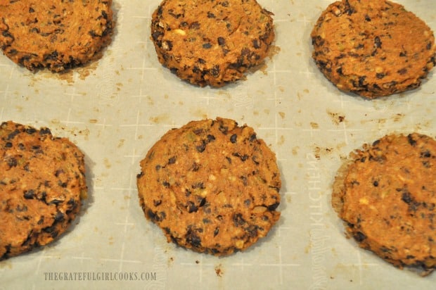 Six black bean burgers on parchment paper, after baking.