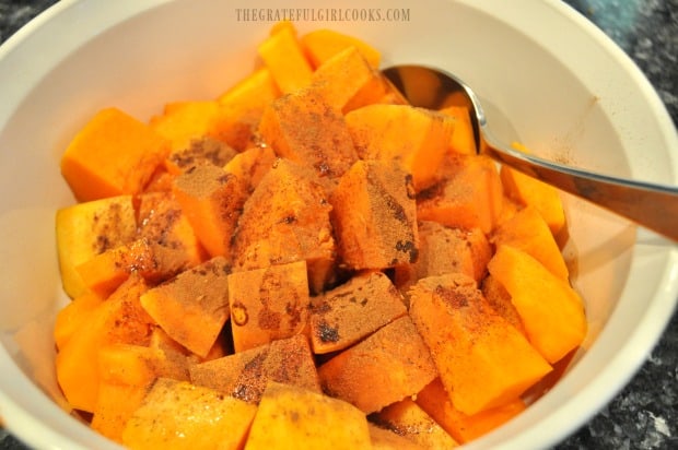Maple syrup and cinnamon are mixed into the butternut squash pieces before baking.