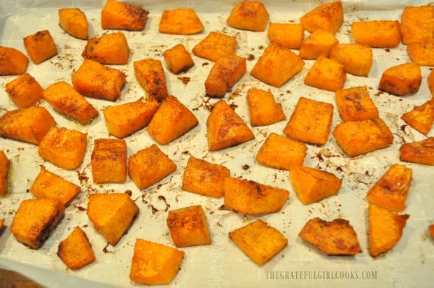 Halfway through baking time, maple cinnamon butternut squash is turned to other side to finish cooking.