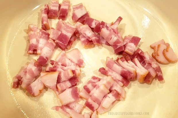 Thinly sliced bacon is cooked to add to fried cabbage.