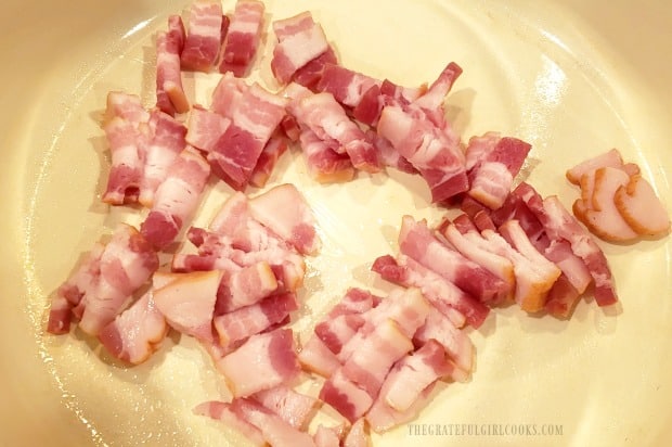 Thinly sliced bacon is cooked to add to fried cabbage.