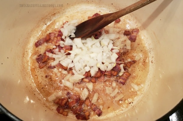 Chopped onions are added to bacon, before adding them to fried cabbage.
