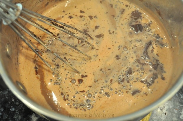 Homemade chocolate pudding mixture is stirred until all chocolate pieces have melted.