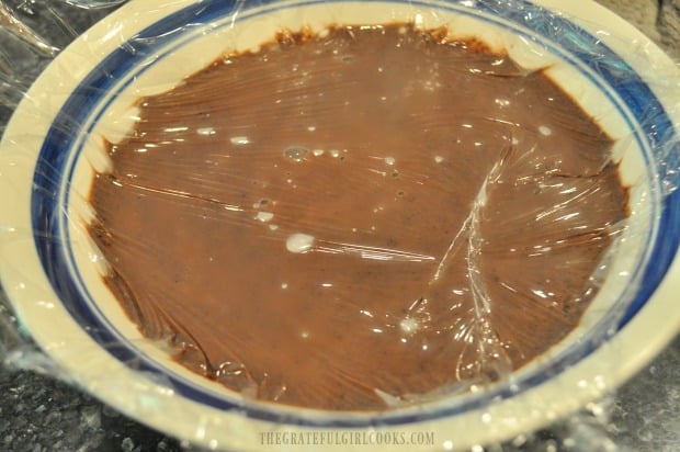 The homemade chocolate pudding is poured into bowl, then covered with plastic wrap, to seal.