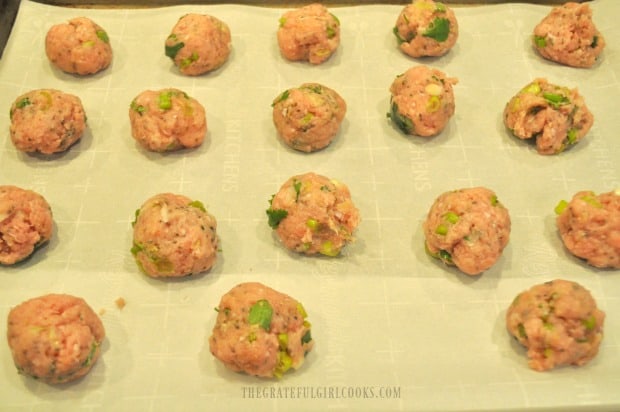 The Thai turkey meatballs on parchment paper lined baking sheet before baking.