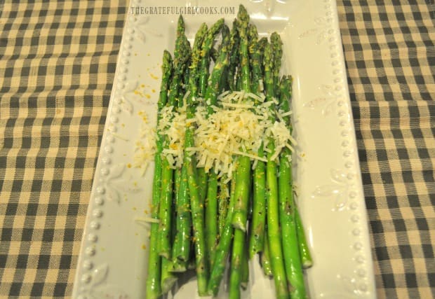 Grilled asparagus is garnished with lemon zest and grated Parmesan cheese, to serve.