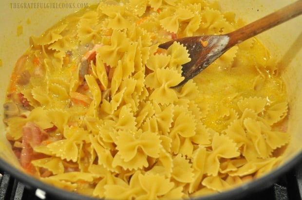 Bow tie pasta noodles are added, to cook in the liquid in saucepan.