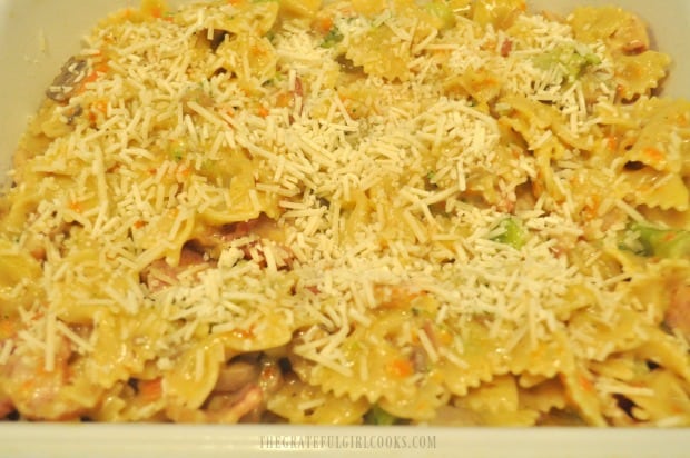 Bacon broccoli pasta casserole is placed in baking dish and topped with Parmesan to bake.